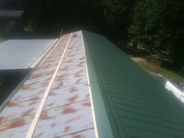 Old rusted panels beside newly installed green metal roofing — Wind Damage Roof Repair by Roofing Brothers in Hiram
