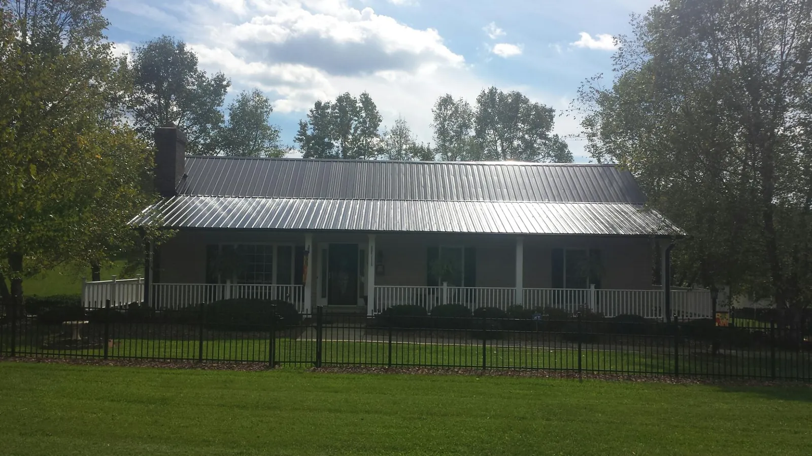 Gray metal roof on a brick ranch with a full width front porch — Gutter Guard Installation work by our crew in Hiram