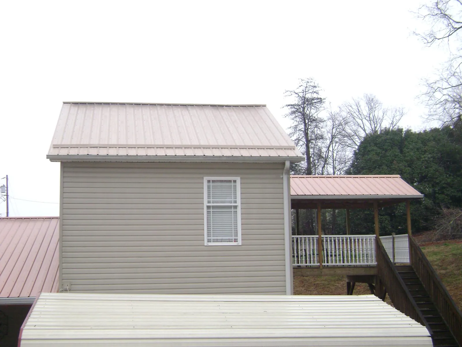 Tan metal roofs on a two story addition and attached porch, from a Roof Replacement job in Hiram